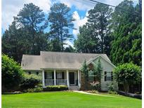Charming home featuring a quaint front porch and beautifully manicured lawn, nestled among mature trees at 60 Stonehedge Dr, Buford, GA 30518