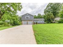 Charming home featuring a two-car garage, stone accents, a spacious lawn, and beautiful mature trees at 4856 Habersham Sw Rdg, Lilburn, GA 30047