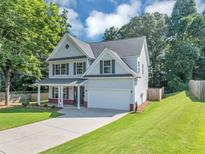 Charming two-story home with a well-manicured lawn, covered porch, and attached two-car garage at 5195 Oaks Landing Ct, Sugar Hill, GA 30518