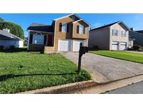 Charming two-story home featuring a manicured lawn and two-car garage at 842 Shoals Ct, Atlanta, GA 30349