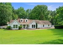 Charming white home boasts a lush green lawn, mature trees, and inviting curb appeal at 145 Deep Step Rd, Covington, GA 30014