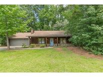 Charming single-story home featuring wood siding, stone accents, and a well-maintained front yard surrounded by mature trees at 800 Greenwood Se Trl, Conyers, GA 30094