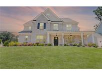 Charming two-story brick home with a manicured lawn and inviting front porch with hanging lanterns at 774 Phil Haven Ln, Kennesaw, GA 30152