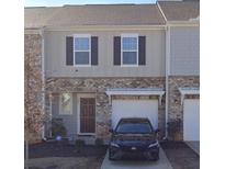 Two-story townhome with brick and siding, a one-car garage, and a manicured front yard at 136 Swindon Dr, Mcdonough, GA 30253