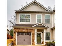 Charming townhouse showcasing a brick-accented garage and inviting front door with a decorative wreath at 7750 Carnegie Dr, Fairburn, GA 30213