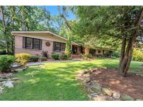 Charming brick home featuring a lush lawn, mature trees, and inviting curb appeal at 2994 Baker Ridge Nw Dr, Atlanta, GA 30318