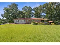 Charming single-story home features a well-manicured lawn, mature trees, and a convenient carport at 6674 Cowan Mill Rd, Winston, GA 30187