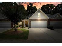 Charming brick townhome featuring a two-car garage and well-maintained landscaping under a dramatic sunset sky at 2521 Eden Ridge Ln # 7, Acworth, GA 30101