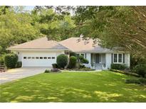Charming single-story home featuring a lush front lawn, attached garage, and manicured landscaping at 1956 Regents Way, Marietta, GA 30062