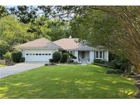 Charming one-story home with a well-manicured lawn, mature trees, and attached two car garage at 1956 Regents Way, Marietta, GA 30062