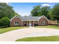 Charming brick home with well-manicured lawn and circular driveway, surrounded by mature trees at 3690 Lithia Way, Lithia Springs, GA 30122