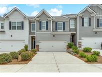 Charming townhome featuring a two-car garage, gray siding, and lovely landscaping at 738 Woodstock Grove Dr, Woodstock, GA 30188