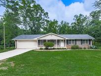 Charming single-story brick home with a well-manicured lawn, tidy landscaping, and an attached garage at 10381 E Cherokee Dr, Canton, GA 30115
