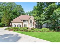 Charming traditional home featuring a manicured front lawn and mature trees at 12160 Oak Hollow Way, Alpharetta, GA 30005