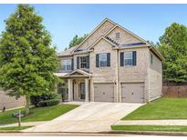 Charming two-story home with a brick facade, well-maintained lawn, and a two-car garage at 219 Sleepy Way, Canton, GA 30114