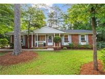 Charming brick home with a well-maintained front yard, mature trees, and inviting front porch at 2703 Carolyn Se Dr, Smyrna, GA 30080