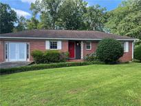 Charming one-story brick home with a well-manicured lawn, mature trees, and a red front door at 2880 Sherwood Se Rd, Smyrna, GA 30082