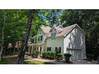 Traditional two-story home features a white exterior, black shutters and attached garage nestled among mature trees at 3618 Prescot Way, Douglasville, GA 30135