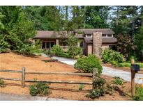 Charming home featuring a stone chimney, lush landscaping, and a welcoming driveway at 3152 Sycamore Ln, Marietta, GA 30066