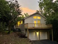 Charming two-story home with a large deck and two car garage nestled among mature trees at sunset at 2268 Sparrow Ridge Ne Dr, Marietta, GA 30066