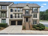 Beautiful townhome featuring a brick and tan exterior with a small front yard and two-car garage at 1165 Laurel Se Pl, Smyrna, GA 30080