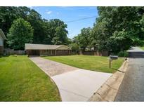 Traditional brick ranch-style home with a well-maintained lawn, mature trees, and a spacious driveway at 3464 Navaho Se Trl, Smyrna, GA 30080