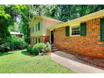 Charming brick home featuring green shutters, established landscaping and a manicured lawn at 2802 Leisure Woods Ln, Decatur, GA 30034