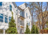 Charming three-story townhouse featuring a balcony, black trim, and well-maintained landscaping at 490 Hammons Way, Atlanta, GA 30315