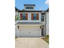 Charming townhome featuring a two-car garage, warm wood shutters, and a beautifully painted white brick facade at 211 N Auburn Landing Pl, Auburn, GA 30011