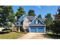 Charming two-story home boasts a blue exterior, stone accents, a well-manicured lawn and an attached two-car garage at 29 Sedgefield Overlook, Dallas, GA 30157
