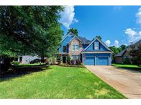 Inviting blue two-story home with stone accents, a well-manicured lawn, and an attached two-car garage at 29 Sedgefield Overlook, Dallas, GA 30157