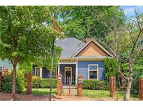 Charming blue home with a brick fence and well-manicured landscaping creates inviting curb appeal at 694 Peeples Sw St, Atlanta, GA 30310