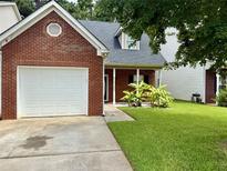 Charming brick home featuring an attached garage and well-manicured lawn at 623 Shadowmoore Dr, Riverdale, GA 30274
