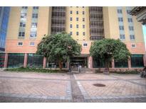 Facade of a multi-story building with trees flanking the entrance and a brick courtyard at 300 Peachtree Ne St # 11I, Atlanta, GA 30308