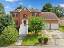 Charming two-story brick home featuring a well-manicured lawn and two-car garage at 1030 Carriage Trace Cir, Stone Mountain, GA 30087