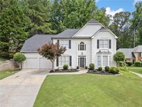 Charming traditional home featuring a manicured lawn, three-car garage, and lush landscaping at 2019 Aldbury Ln, Woodstock, GA 30189