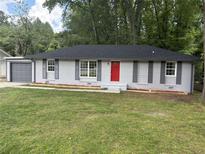 Charming one-story home featuring freshly painted brick, black roof, a vibrant red front door, and a well-manicured front yard at 8236 Tudor Dr, Jonesboro, GA 30238