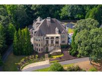 Beautiful stone home featuring manicured landscaping, stately columns, and a circular driveway at 11140 W Rd, Roswell, GA 30075
