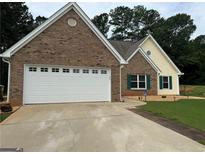 Charming brick and siding home featuring an attached garage and well-maintained front lawn at 521 Deadwood Trl, Locust Grove, GA 30248