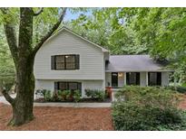 Charming two-story home with white painted brick and vinyl siding nestled in a wooded lot with mature trees at 2377 Emory Ln, Marietta, GA 30068