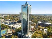 A modern skyscraper with reflective glass, nestled in a vibrant green landscape and neighborhood views at 2828 Peachtree Nw Rd # 1502, Atlanta, GA 30305