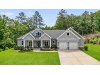 Charming, single-story home with a two-car garage, gray siding, covered porch, and manicured lawn at 287 Flower Farm Dr, Acworth, GA 30101