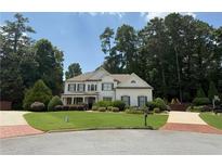 Inviting two-story home with a lush lawn, manicured landscaping, and a brick driveway, surrounded by mature trees at 970 Tarpley Nw Rd, Kennesaw, GA 30152