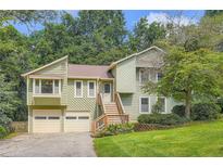 Inviting home with two-car garage, green siding, and well-maintained front yard at 5093 Ravenwood Dr, Marietta, GA 30066