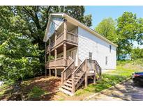 Two-story home with double balconies, wooden steps, and charming curb appeal surrounded by lush trees at 1112 Smith St, Atlanta, GA 30310