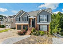 Charming two-story home features a gray exterior, brick accents, and a well-maintained front yard with colorful flowers at 680 Harbor Point Ct, Lawrenceville, GA 30044