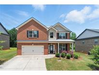 Charming two-story brick home with a well-maintained lawn and attached two-car garage with concrete driveway at 2445 Whitehead Place Dr, Suwanee, GA 30024