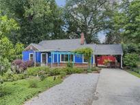 Charming blue cottage-style home with lush landscaping, quaint pergola, and convenient carport at 5130 Dearing St, Covington, GA 30014