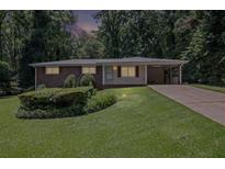 Charming brick home featuring a well-manicured lawn and covered carport at 4051 Dixie Ln, Douglasville, GA 30135