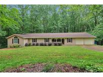 Ranch-style home with well-maintained lawn, mature trees, and attached two-car garage at 7704 Holyoke Rd, Cumming, GA 30040